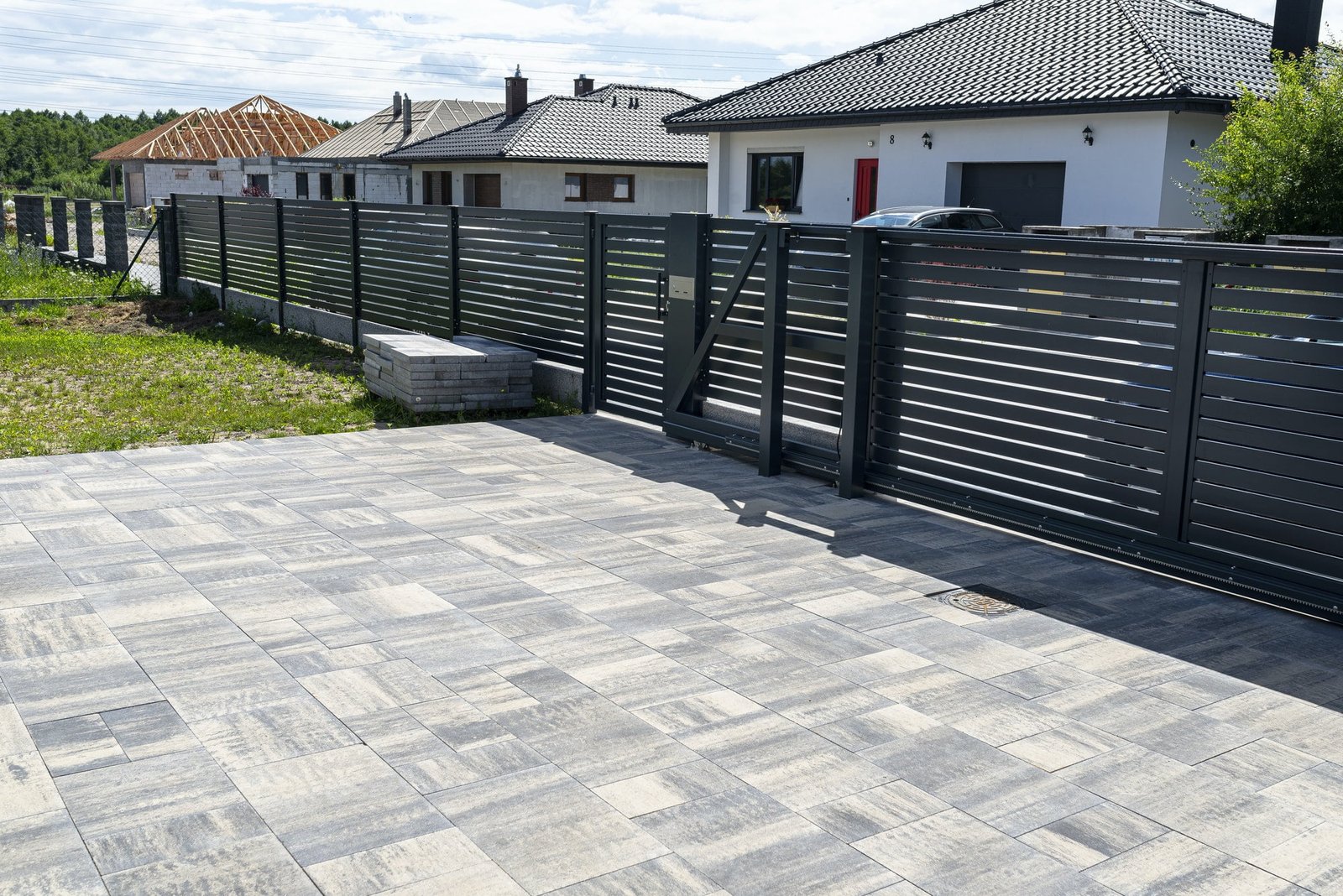 A modern panel fence in anthracite color, a visible sliding gate to the garage and a wicket.