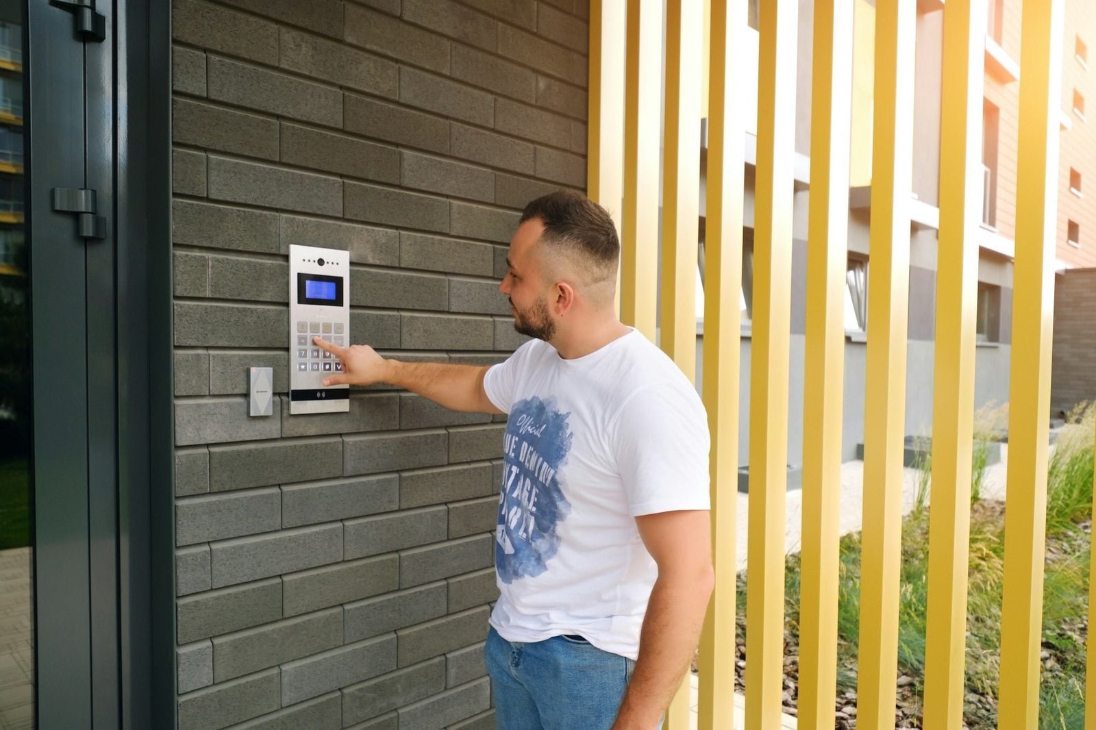 Man stands at the residential building and dials the code from the intercom door
